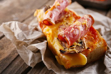 Hot pizza baguette with bacon, mushrooms and cheese on wooden table