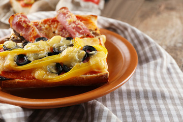 Hot pizza baguettes with paprika, bacon, olives and cheese on wooden table