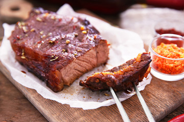 Sliced roasted pork steak with meat fork and spices on wooden background
