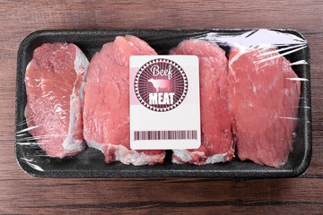 Packed pieces of beef meat on wooden background