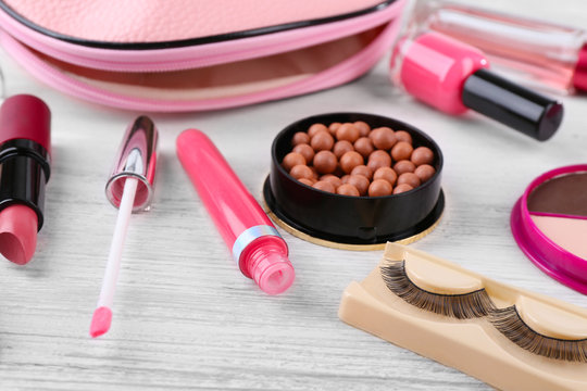 Makeup set with beautician, false eyelashes and cosmetics on white wooden background