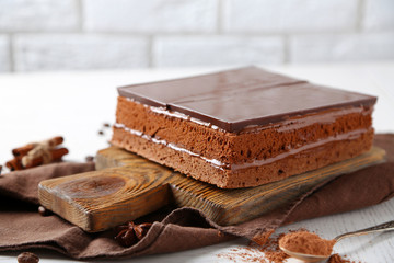 Delicious chocolate cake on wooden cutting board closeup