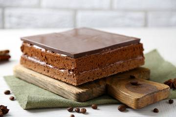 Delicious chocolate cake on wooden cutting board closeup