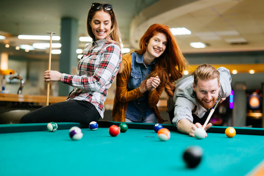 Happy friends enjoying playing pool