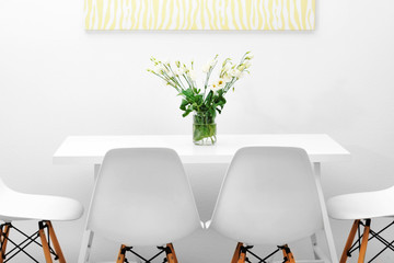 Modern dining room. White chairs and table with bouquet of flowers, abstract picture on the wall