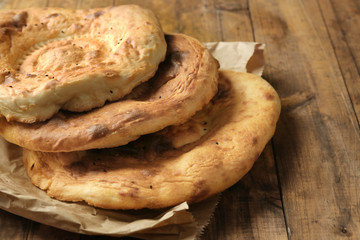 Flat bread on craft paper on wooden background