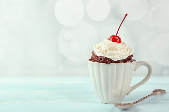 Chocolate mug cake with cream and cherry on a table