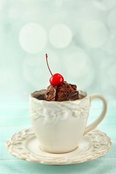 Chocolate mug cake with cream and cherry on a table