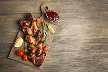 Baked chicken wings with tomatoes and rosemary on cutting board