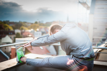 young man doing stretching against a blurred cityscape