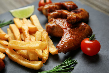 Baked chicken wings with French fries on slate plate