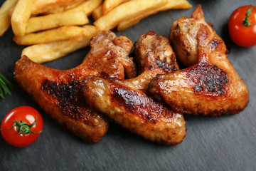 Baked chicken wings with French fries on slate plate
