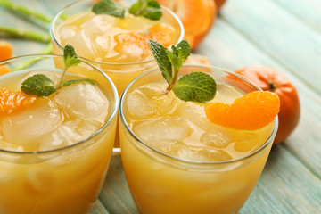 Fresh cocktails with ice, mint and tangerines on the wooden table, close up