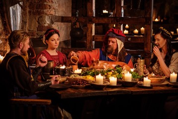 Medieval people eat and drink in ancient castle kitchen interior.