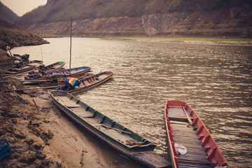 old wooden fishing boats at the side of a river in Thailand
