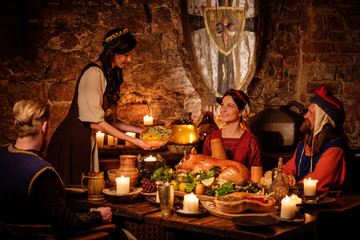 Medieval people eat and drink in ancient castle kitchen interior