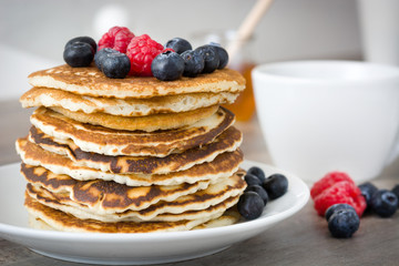 Sweet pancakes with blueberries and raspberries pon rustic wood


