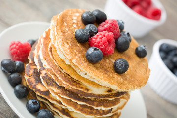 Sweet pancakes with blueberries and raspberries pon rustic wood

