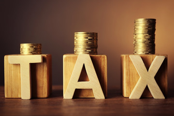 Word tax with stacked coins on dark background