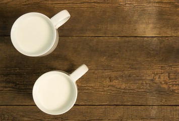 Fototapeta na wymiar Two cups with cold milk on the wooden table 