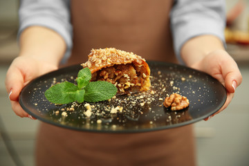 Woman holding plate with an apple roll