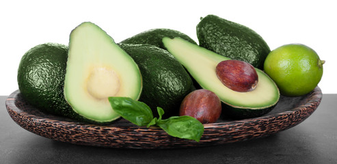 Wooden plate full of avocados on a white background