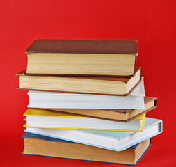 Stack of new and old books on red background