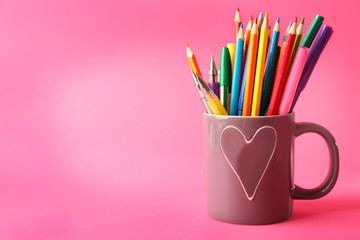 Colorful stationery in cup on pink background