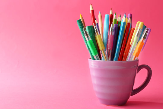 Colorful stationery in purple cup on pink background