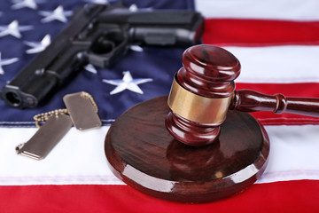 Gavel with gun and tokens on background of USA flag