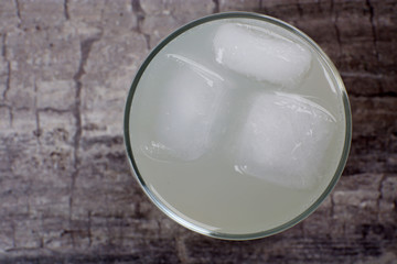 Fototapeta na wymiar Glass of lemon soda with ice on rustic wooden background