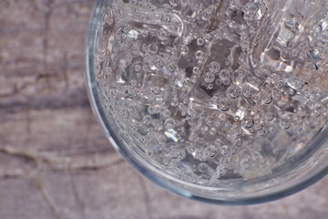 Glass of soda with ice on rustic wooden background