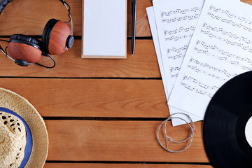 Headphones, music sheets and straw hat on wooden surface, top view