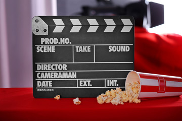 Movie clapper and popcorn on blurred background