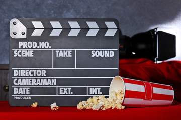 Movie clapper and popcorn against grey wall background