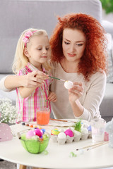 Obraz na płótnie Canvas Mother and daughter decorating Easter eggs, indoors