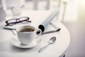 White cup of the coffee on wooden table  in a light room..