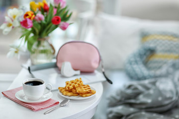 White cup of the coffee and sweets on wooden table  in a light room..