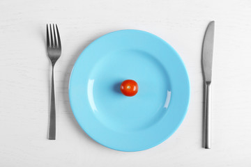 Cherry tomato in a blue plate on white table. Top view.