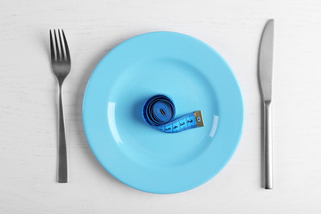 Measuring tape in empty plate on white table.. Top view.