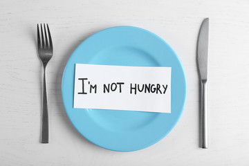 Words I'm not hungry in a plate on white table. Top view.