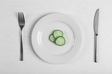 Pieces of cucumber in a white plate on white table. Top view.