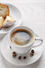 Cup of coffee with cake on light wooden background