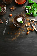 Glass cup of chocolate dessert with fresh mint and frothed milk on black wooden table
