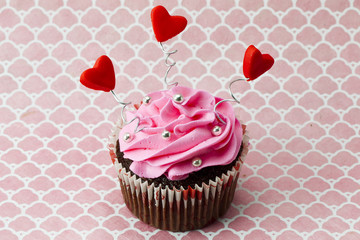 a strawberry cupcake with heart shapes and beads.