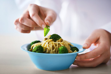 Chef hands preparing delicious cold pasta salad closeup