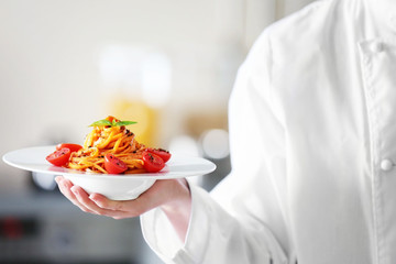 Chef hand holding delicious cold pasta salad in bowl on the table closeup