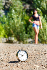 clock on the stone road and blurred girl at sunny day.
