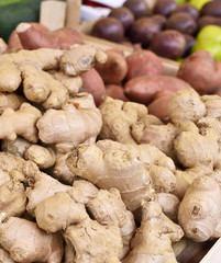 Fresh ginger at a market stall. Weekly market place with fresh vegetables and fruits. Selective focus of ginger in a wooden box at a market stall. 