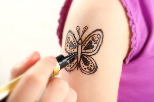 Image of butterfly painted with henna on girl's arm closeup